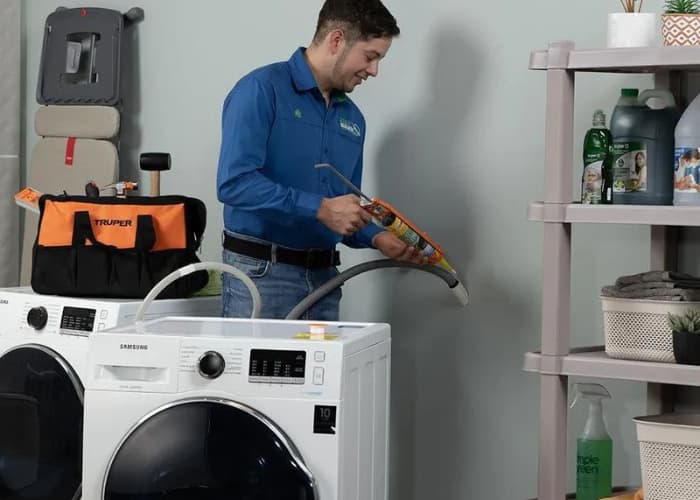 Técnico de Solution part realizando la instalación de una lavadora Samsung, asegurando las conexiones de desagüe con precisión...