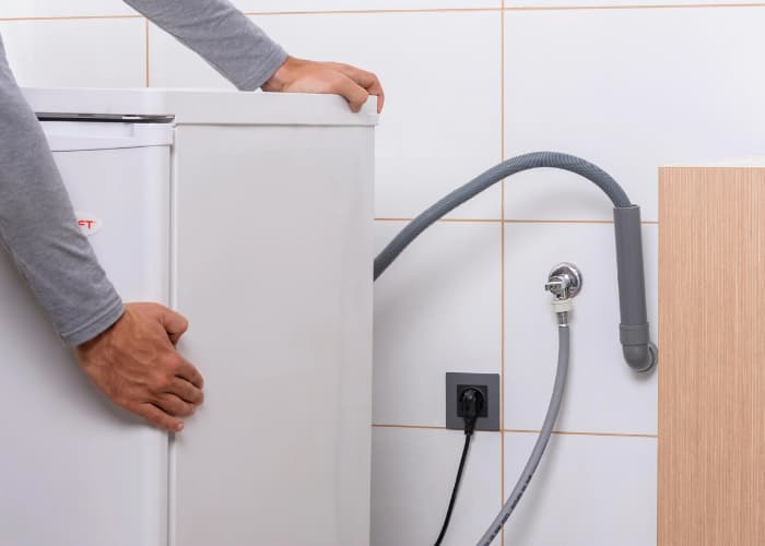 Técnico de Solution part conectando el desagüe y la toma de agua en la fase final de la instalación de una lavadora.