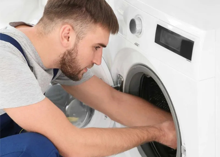 Experto de Solution Part realizando la instalación profesional de una secadora de ropa, verificando conexiones.