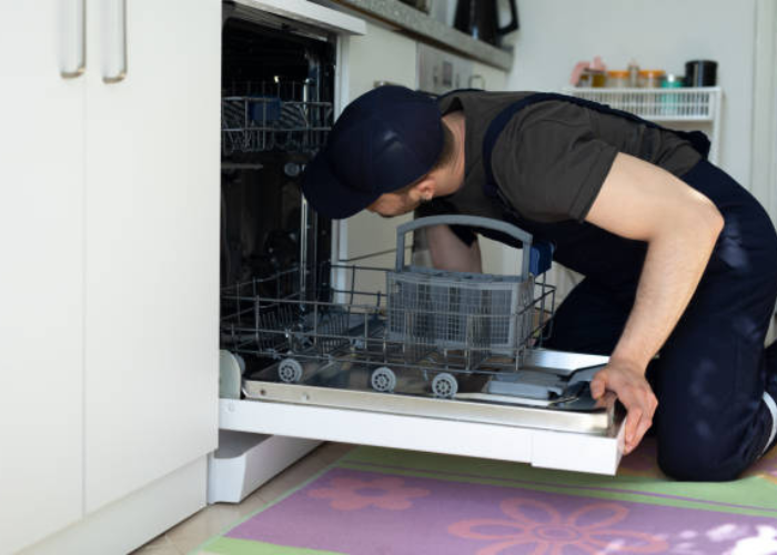 Instalador de lavavajillas de Solution Part revisando conexiones internas en un lavavajillas empotrado..