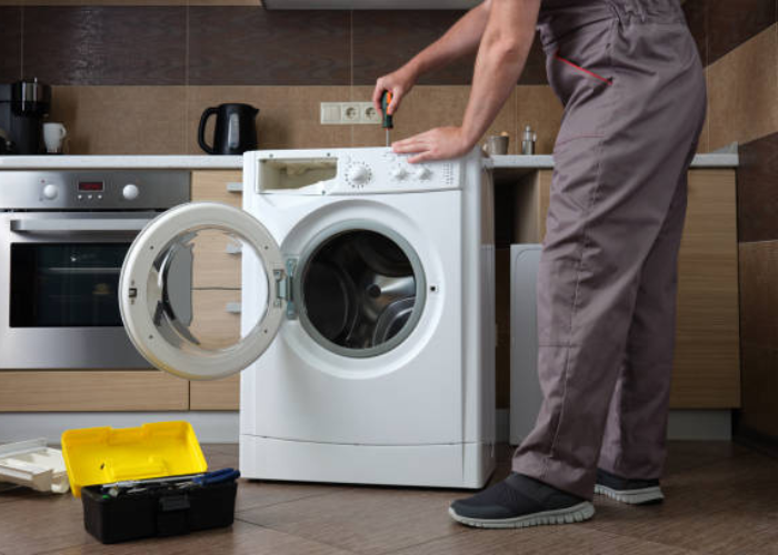 Técnico de Solution Part reparando una lavadora a domicilio en una cocina moderna..