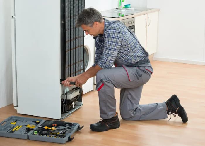 Técnico experto de Solution Part realizando la reparación de un refrigerador en una casa en Viña del Mar, con su caja de herramientas profesionales..