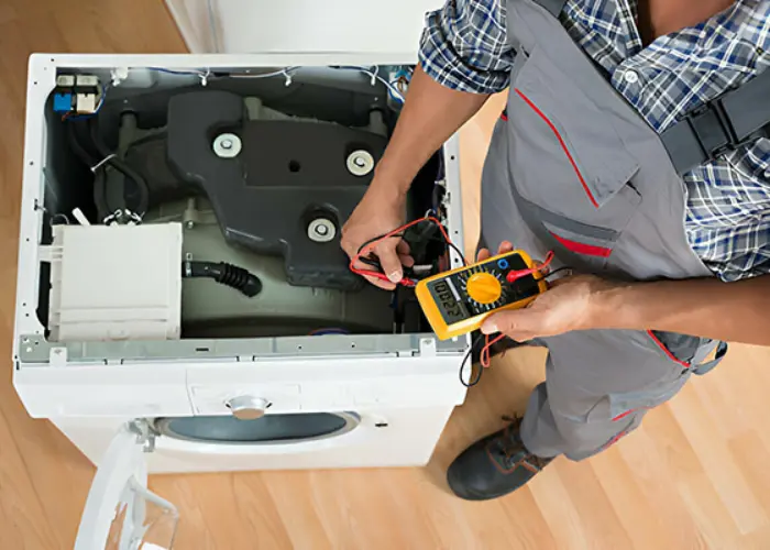 Un técnico de Solution part revisa una lavadora con un multímetro.