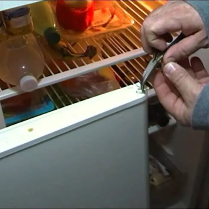 Técnico de Solution Part reparando con precisión la bisagra de la puerta de un refrigerador para garantizar un sellado y cierre perfectos.