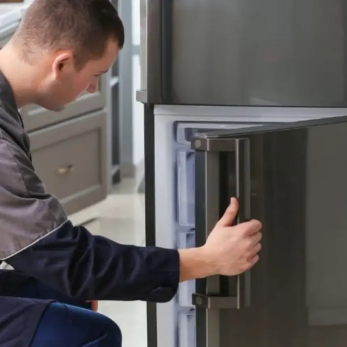 Técnico especialista de Solution Part inspeccionando el compartimiento del fabricador de hielo dentro del congelador de un refrigerador.