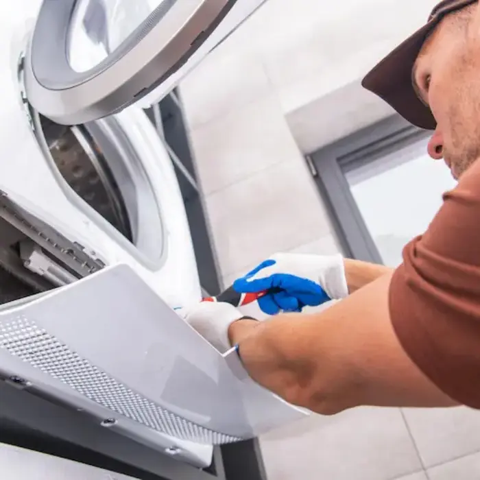 Técnico de Solution Part con guantes, realizando el mantenimiento del filtro y la bomba en la parte inferior de una lavadora Bosch.